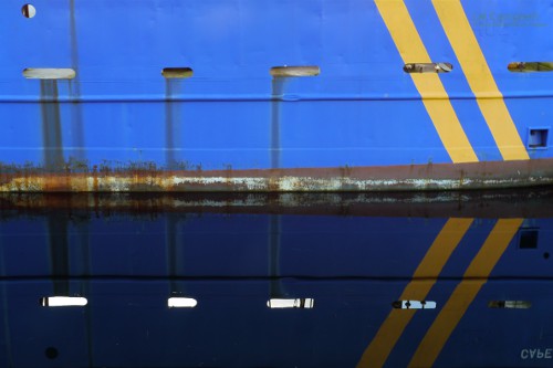 Yellow stripes on a ship reflecting on water create arrows
